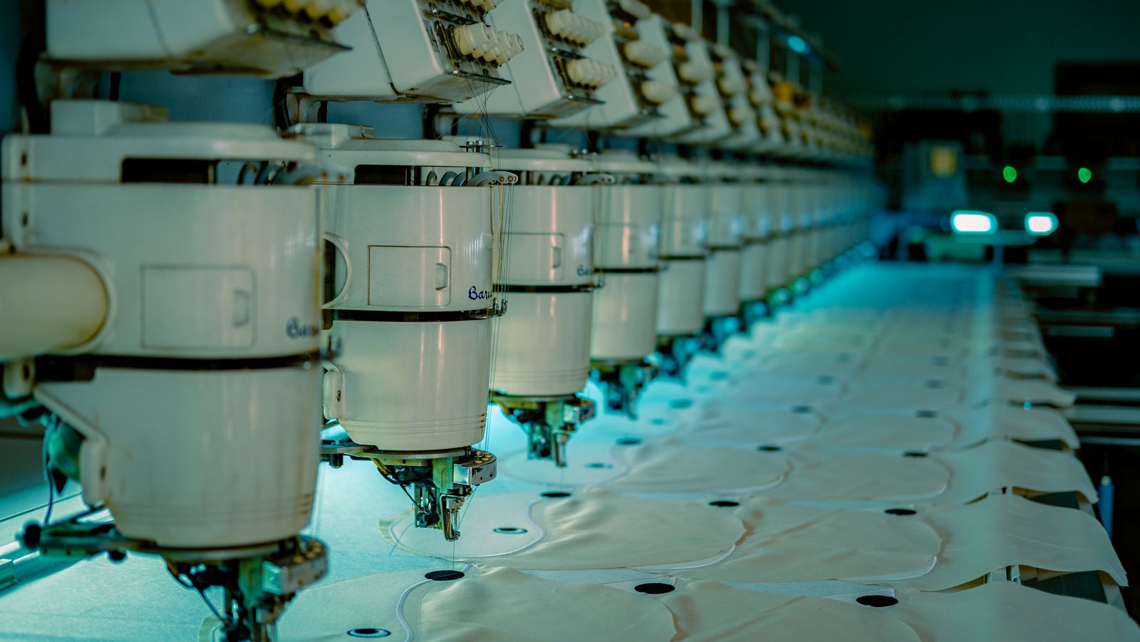 Row of industrial embroidery machine heads stitching fabric